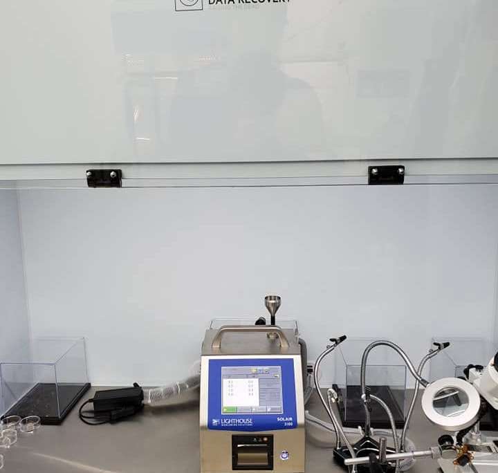 Lighthouse SOLAIR 3100 particle counter running inside a Tri-State Data Recovery ISO Class 4 flow hood alongside recovery tooling