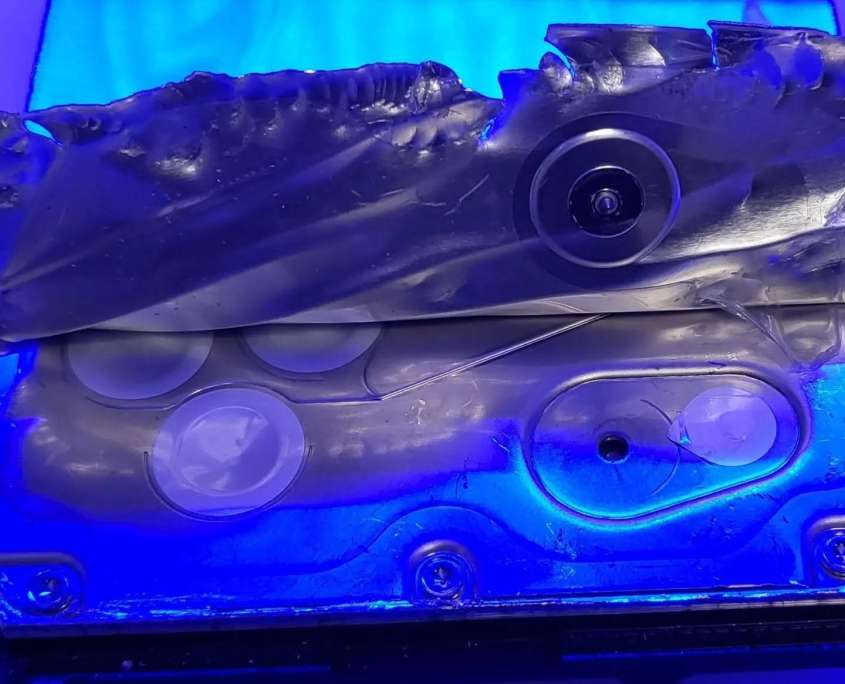 The factory hermetic foil seal peeled back from a helium-sealed hard drive lid, exposing the fill port beneath