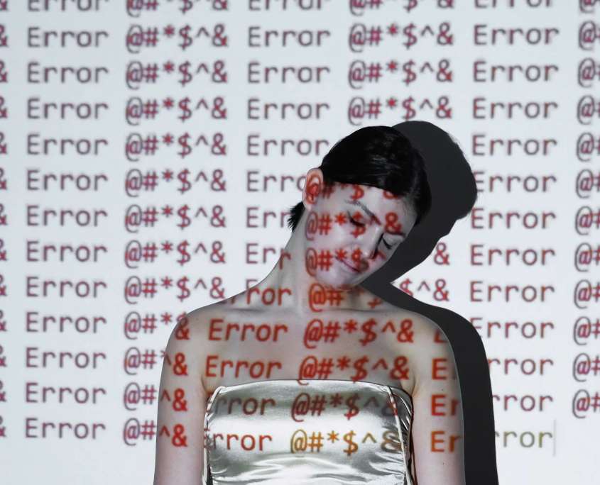 A person standing with head bowed and eyes closed as repeated error messages are projected across them and the wall behind, illustrating a failing hard drive throwing read errors